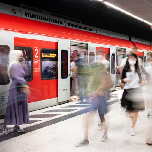 Das Bild zeigt eine U-Bahn. Sie hält am Bahnsteig. Fahrgäste steigen ein und aus.