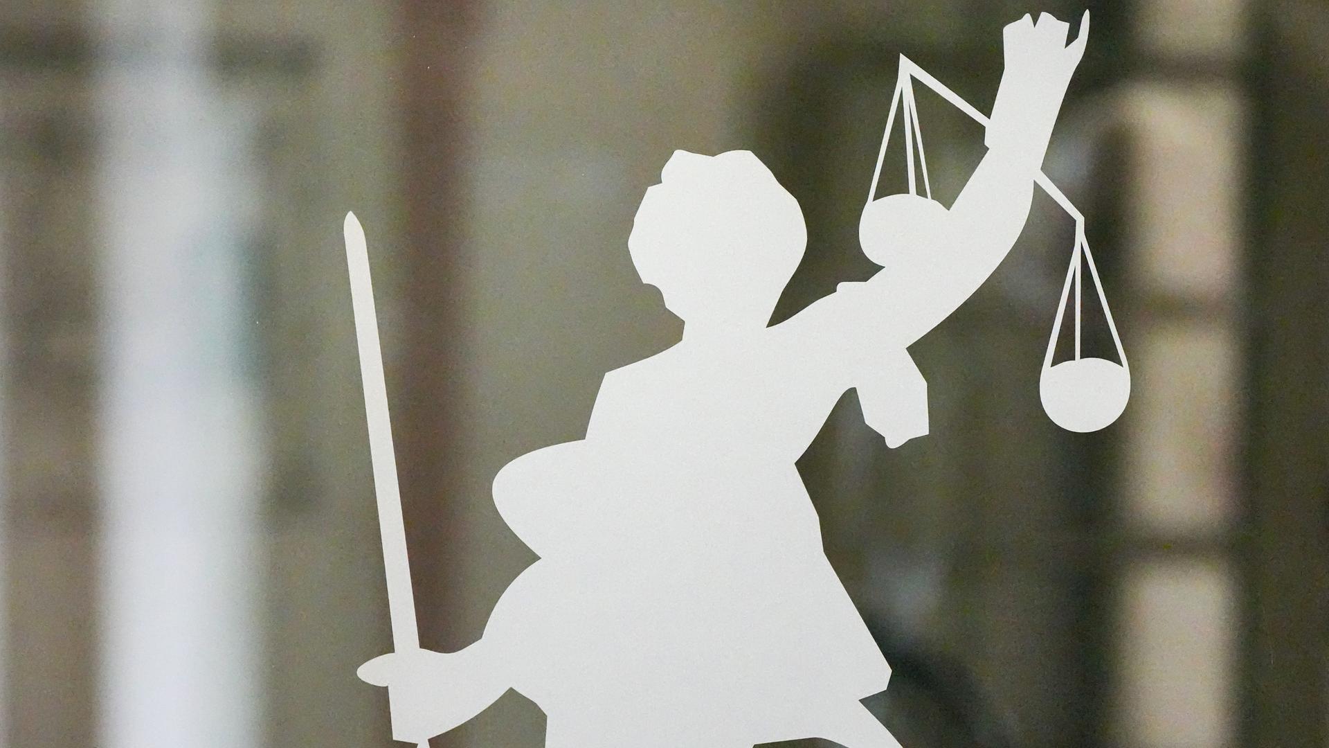 Die Figur der Justitia mit Richtschwert und Waage ist auf dem Glasfenster einer Tür im Gerichtsgebäude zu sehen