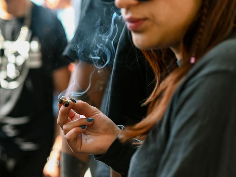 Eine junge Frau raucht einen Joint.