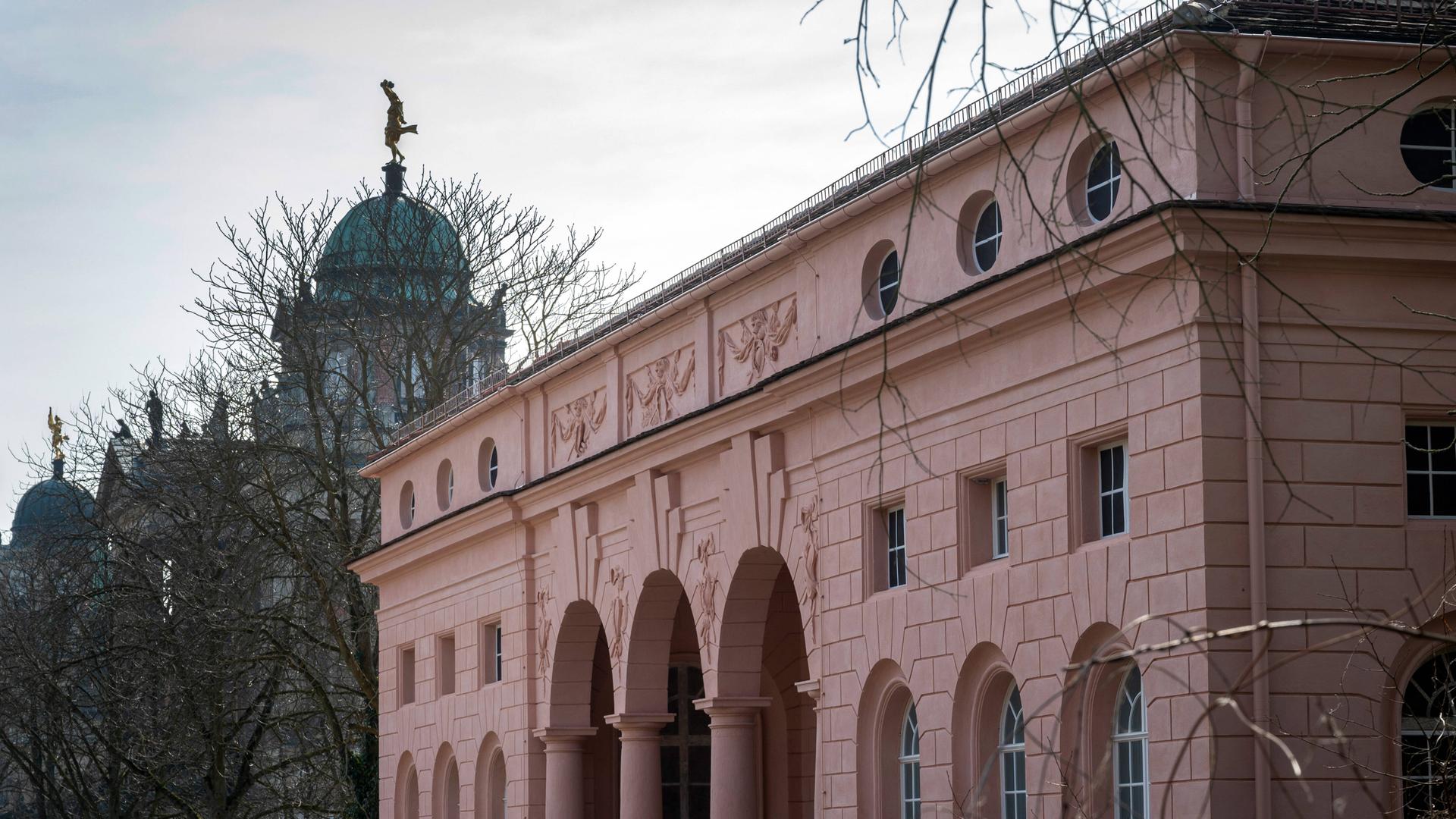 Ein rötliche gestrichenes Gebäude mit drei Säulen und Rundbögen am Eingang. Ein rötliche gestrichenes Gebäude mit drei Säulen und Rundbögen am Eingang.