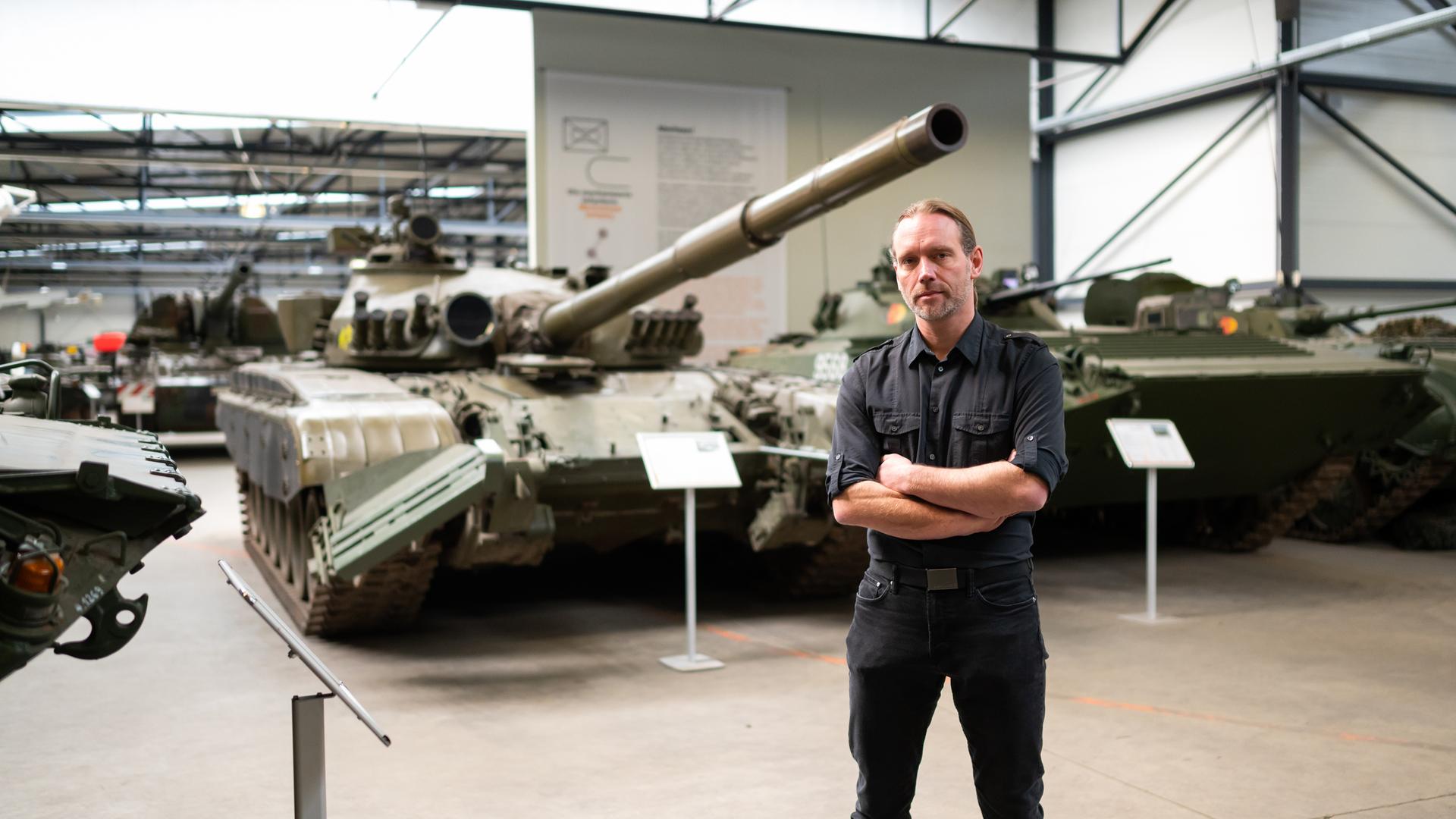 Ralf Raths steht mit verschränkten Armen vor alten Panzern der NVA. Ralf Raths steht mit verschränkten Armen vor alten Panzern der NVA.