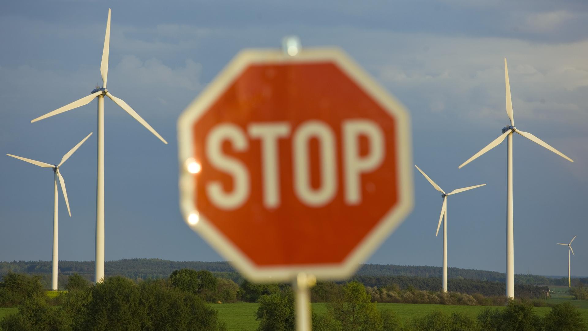 Ein Stop-Schild steht an einer Straße vor Windrädern Ein Stop-Schild steht an einer Straße vor Windrädern
