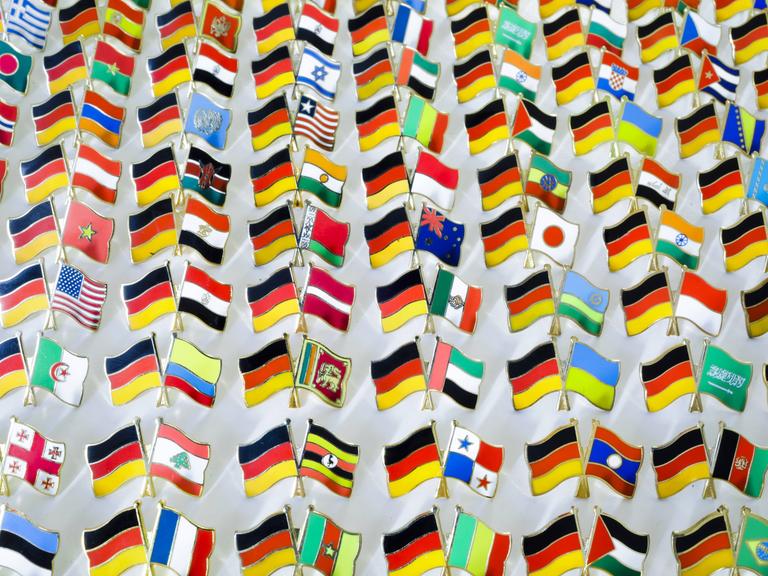 Pins mit den kombinierten Nationalflaggen von Deutschland und vielen verschiedenen Staaten stehen auf einem Tisch in Berlin.