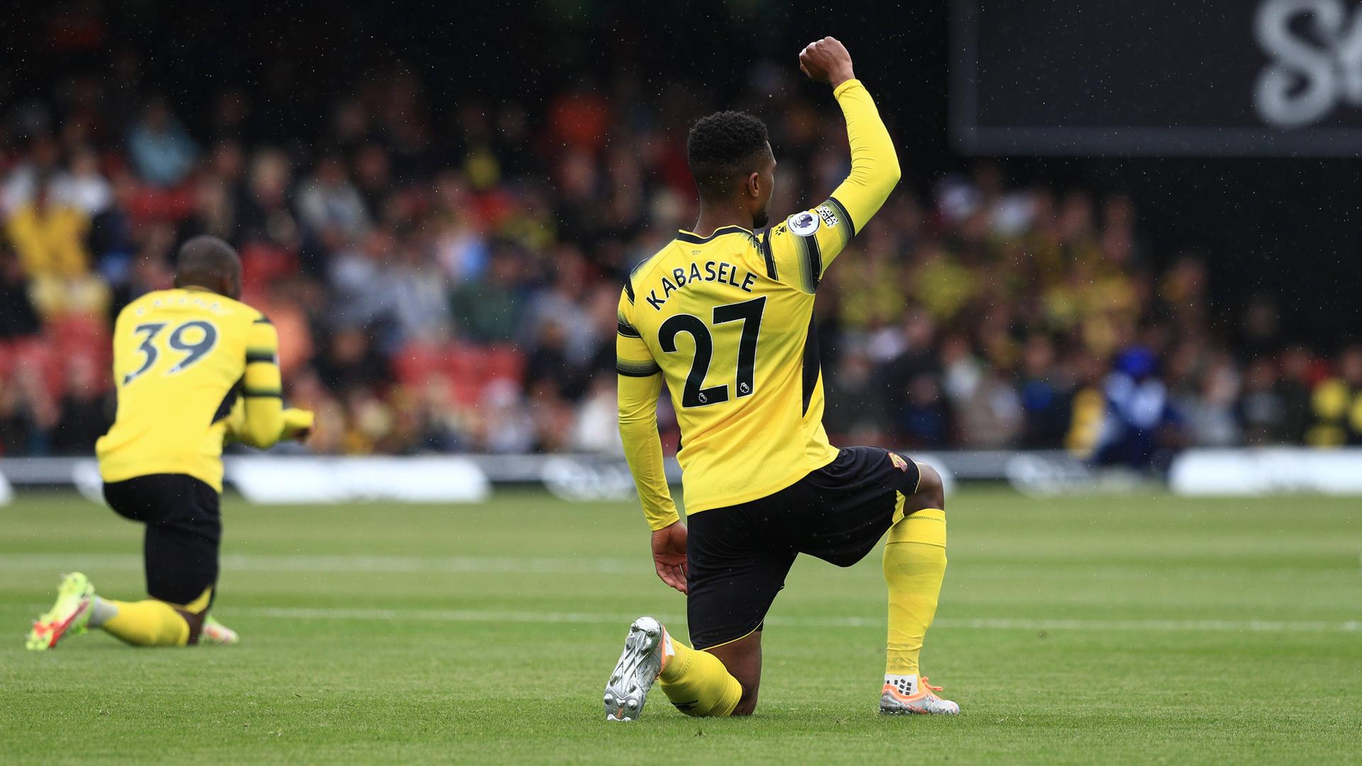 Die Watford-Spieler Christian Kabasele und Edo Kayembe knien vor dem Premier-League-Spiel gegen Leicester City am 15. Mai 2022. Die Watford-Spieler Christian Kabasele und Edo Kayembe knien vor dem Premier-League-Spiel gegen Leicester City am 15. Mai 2022.
