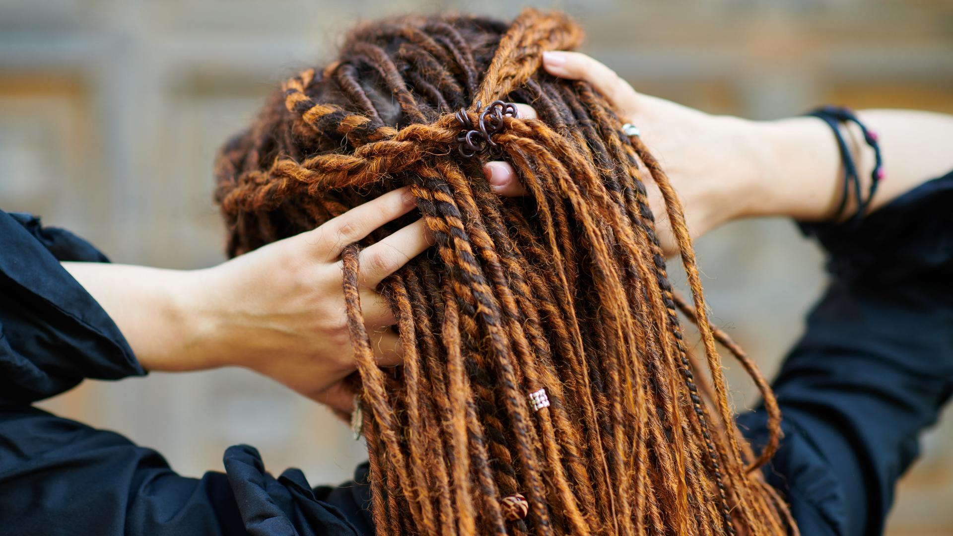 Eine weiße Frau fasst sich am Hinterkopf in ihre Dreadlocks. Eine weiße Frau fasst sich am Hinterkopf in ihre Dreadlocks.