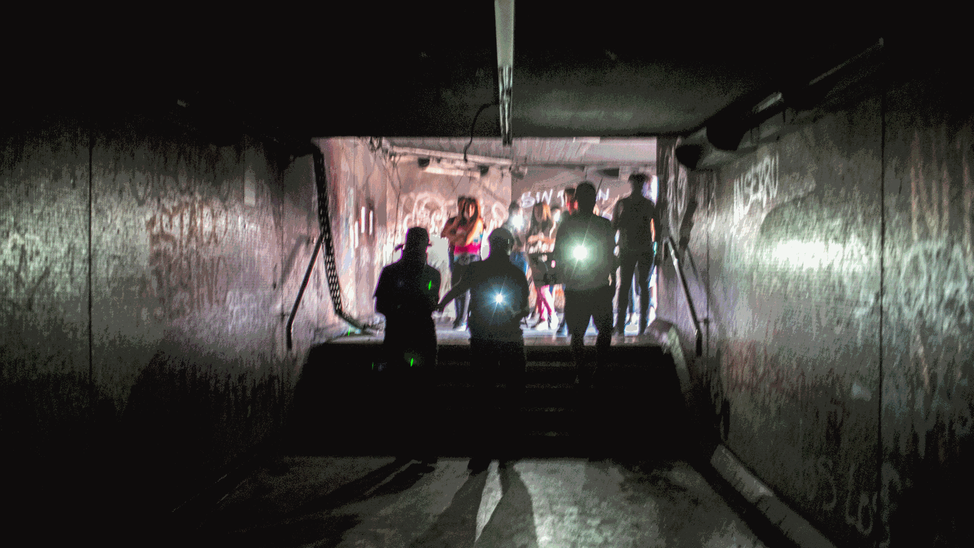 In einem Tunnel sind im Hintergrund Menschen mit Taschenlampen. In einem Tunnel sind im Hintergrund Menschen mit Taschenlampen.