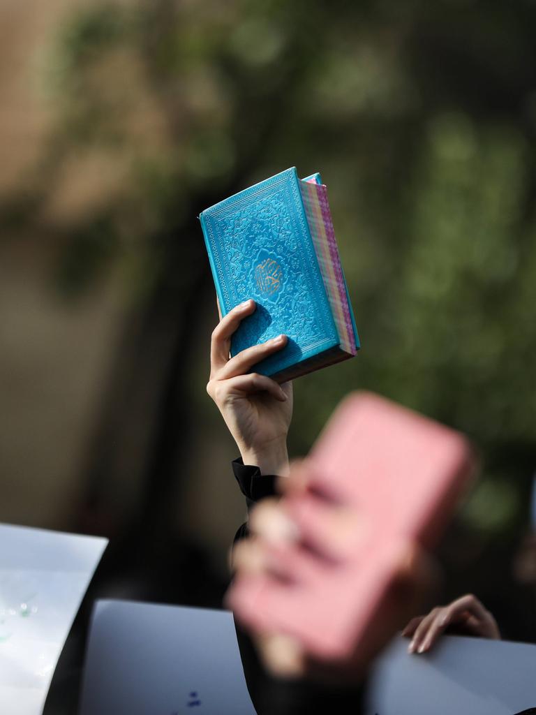 Eine hand hält bei einer Demonstration den blau eingebundenen Koran in die Höhe.