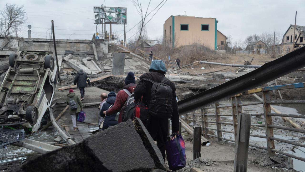 Menschen fliehen aus einer zerstörten Stadt.