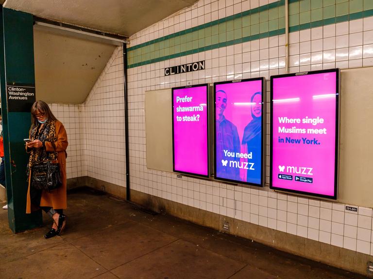 Pinke Plakate mit einem muslimischen Paar und der Aufschrift "Where single Muslims meet in New York" hängen auf einem New Yorker U-Bahnhof.