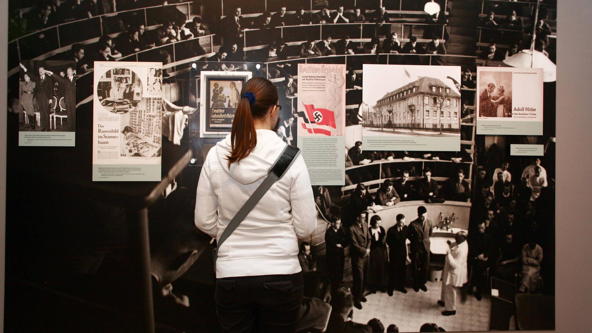 Ausstellung - Tödliche Medizin: Rassenwahn im Nationalsozialismus - im Jüdischen Museum in Berlin / Besucherin vor einem Bild, welches eine Vorlesung an der Berliner Charite zeigt