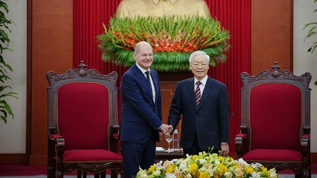 Bundeskanzler Olaf Scholz (SPD) wird von Nguyen Phu Trong (r), Generalsekretär der Kommunistischen Partei, empfangen. Beide lächeln.