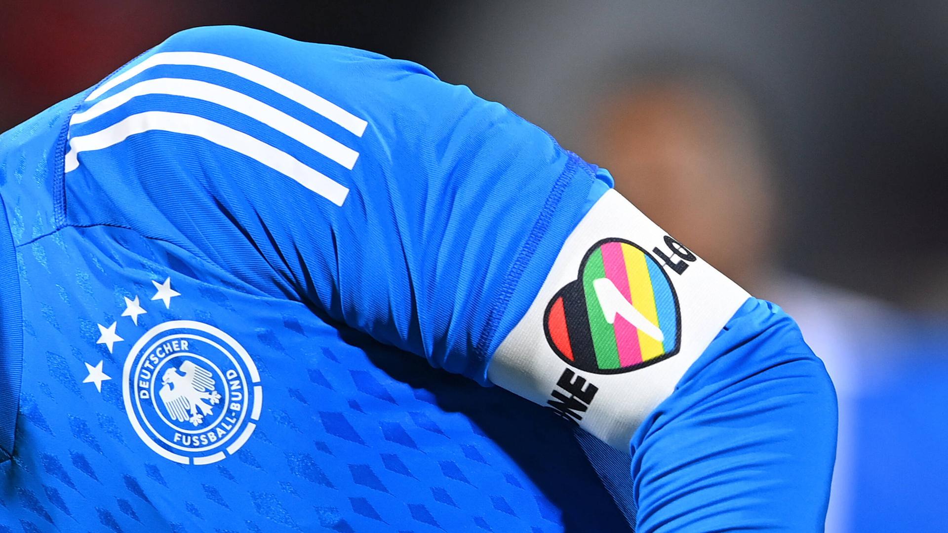 Am Arm eines blauen Trikots von Torwart Manuel Neuer sieht man die Armbinde mit der Aufschrift "One Love". Am Arm eines blauen Trikots von Torwart Manuel Neuer sieht man die Armbinde mit der Aufschrift "One Love".