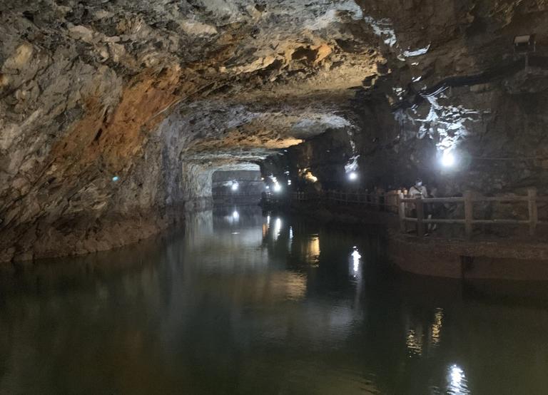 In dem dunklen Tunnel hängen an den Steinwänden rechts in gegelmäßigen Abständen brennende Lampen. Der Boden ist mit Wasser bedeckt. In dem dunklen Tunnel hängen an den Steinwänden rechts in gegelmäßigen Abständen brennende Lampen. Der Boden ist mit Wasser bedeckt.