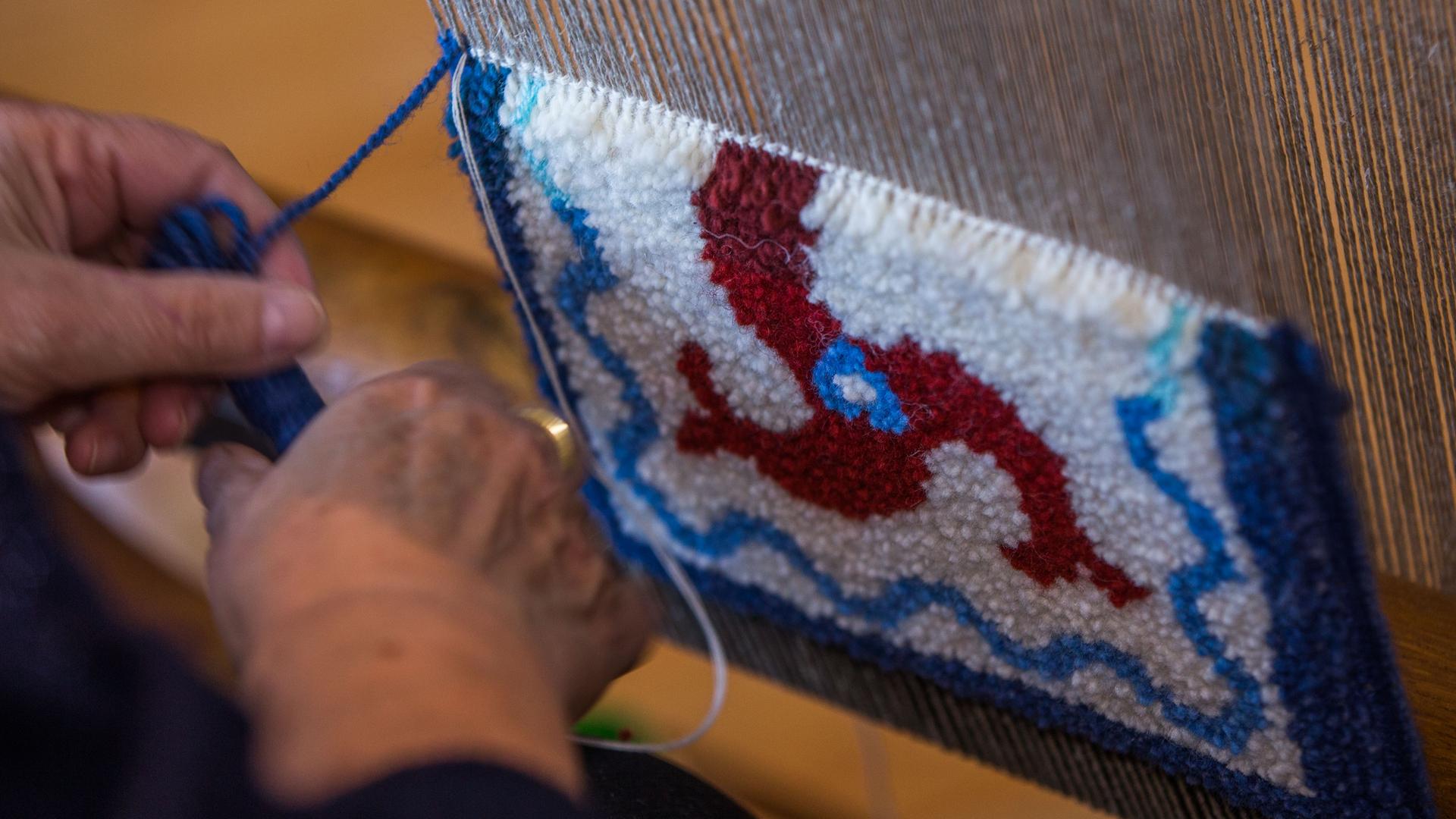 Frauenhände knüpfen einen Fischerteppich mit dem Motiv des Drefisch. Frauenhände knüpfen einen Fischerteppich mit dem Motiv des Drefisch.