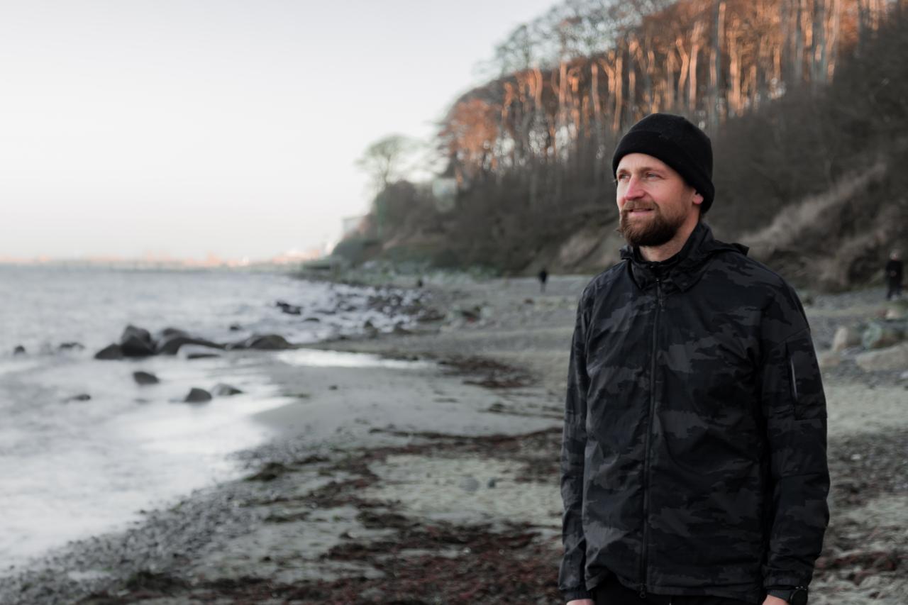 Micha, Sportlehrer und Fußballtrainer aus Köln, steht am Wasser und schaut auf das Wasser hinaus.
Micha, Sportlehrer und Fußballtrainer aus Köln, steht am Wasser und schaut auf das Wasser hinaus.