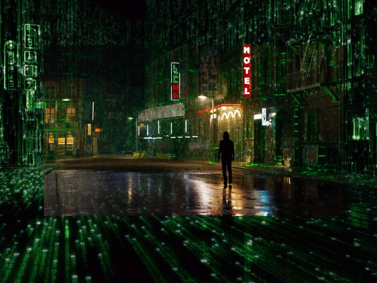 Filmszene aus Matrix 4 Resurrections von Lana Wachowski mit Keanu Reeves. Zu sehen ist eine dystopisch anumtende Stadt in nächtlicher Beleuchtung.