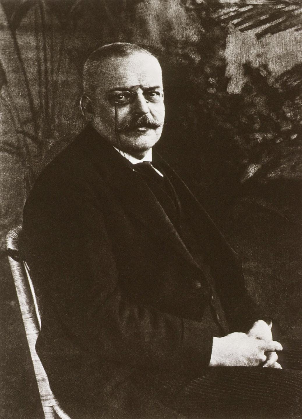Ein undatiertes Schwarz-Weiß-Foto von Alois Alzheimer. Ein älterer Herr mit Brille und im Anzug sitzt auf einem Stuhl. 