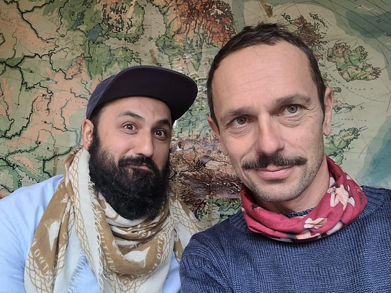 Selfie von Florian Schönhofer und dem Arzt Atal Rasoul vor einer Landkarte.