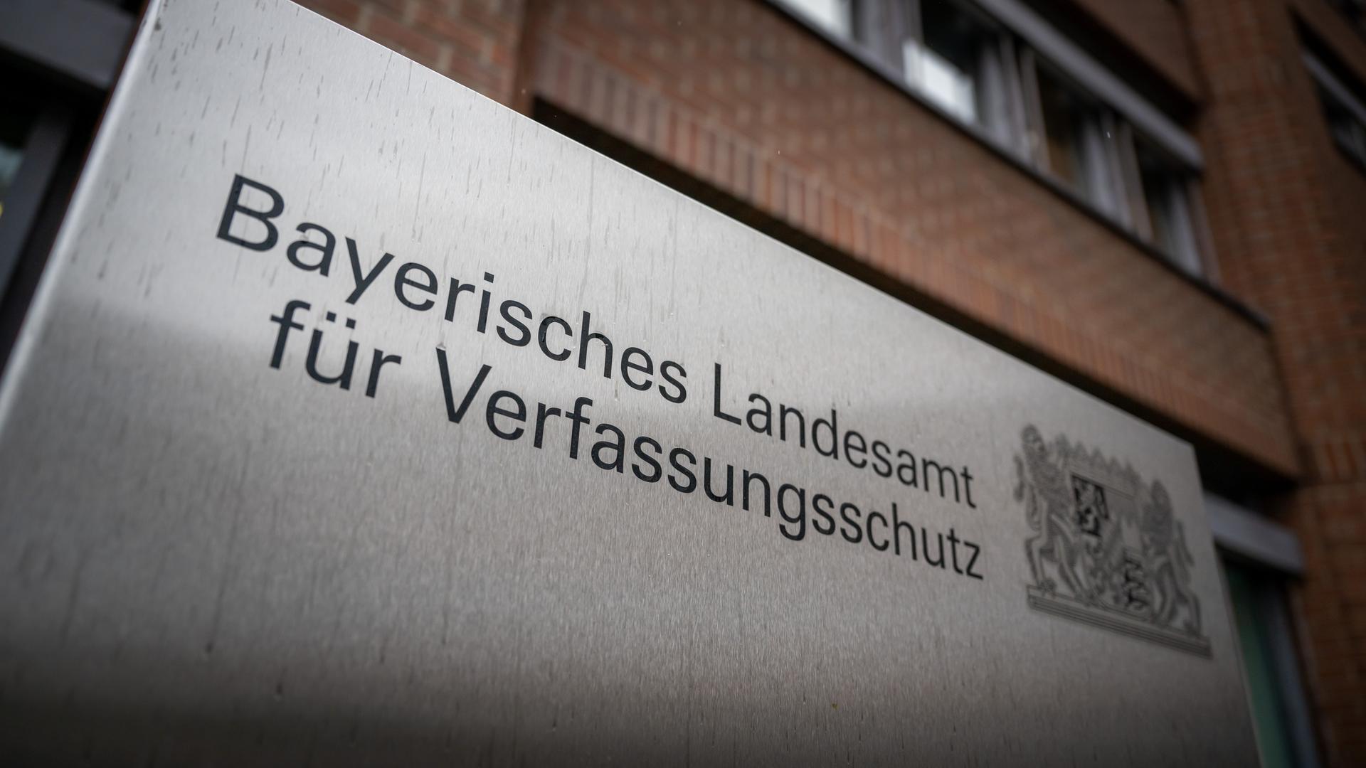 Ein Metallschild mit der Aufschrift «Bayerisches Landesamt für Verfassungsschutz» steht vor dem Gebäude der Einrichtung.