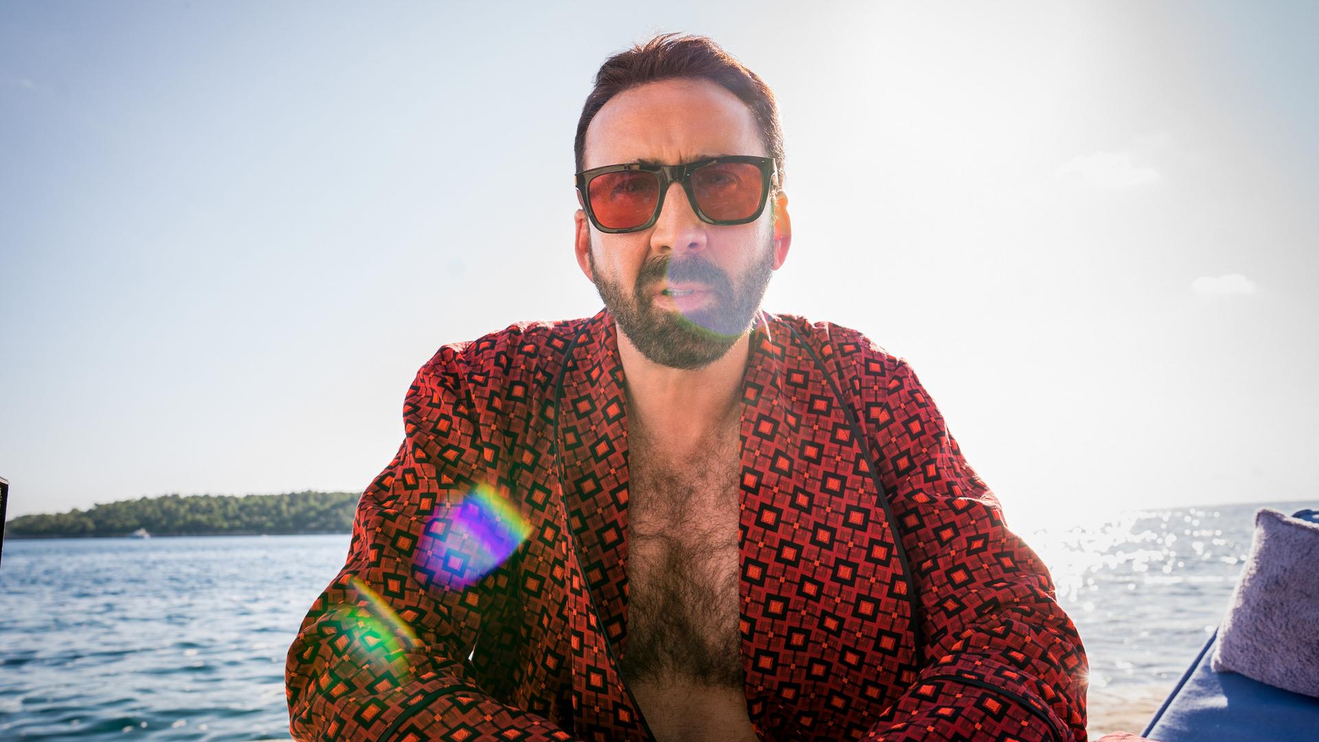 Nicolas Cage sitzt im Gegenlicht scheinbar in einem Boot auf dem Meerm trägt Sonnenbrille und schaut in die Kamera. Nicolas Cage sitzt im Gegenlicht scheinbar in einem Boot auf dem Meerm trägt Sonnenbrille und schaut in die Kamera.