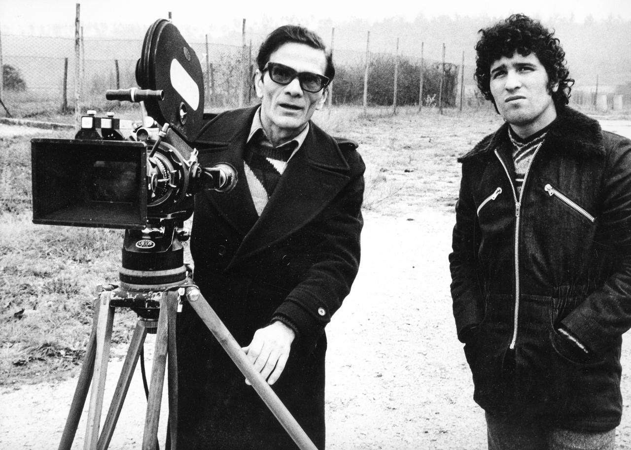 Pier Paolo Pasolini und Ninetto Davoli stehen an einem Filmset hinter der Kamera.