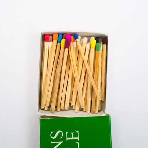 Streichhölzer mit verschiedenfarbigen Köpfen in einer geöffneten Schachtel vor hellem Hintergrund
