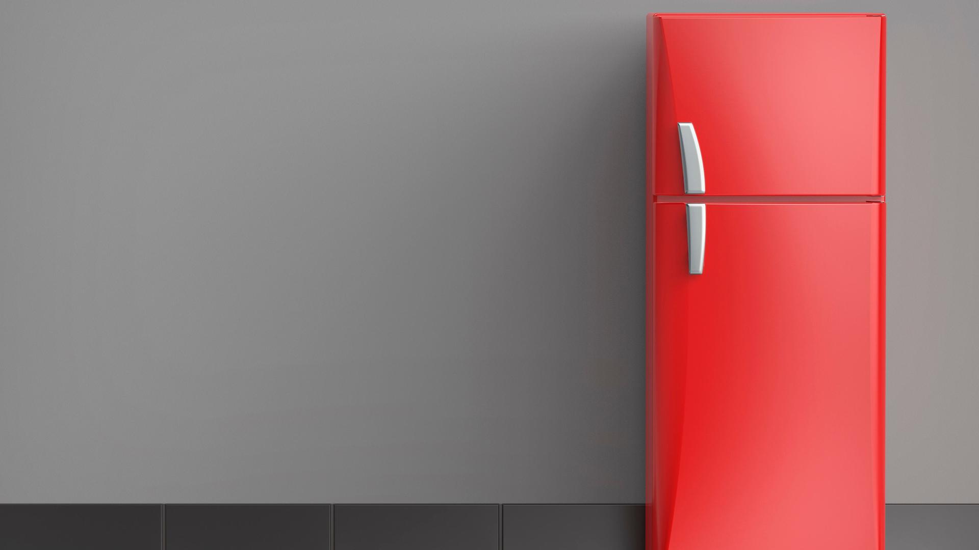 Ein roter Kühlschrank steht vor einer Wand.