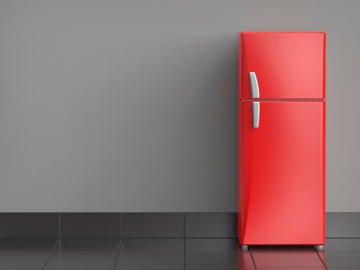 Ein roter Kühlschrank steht vor einer Wand.
