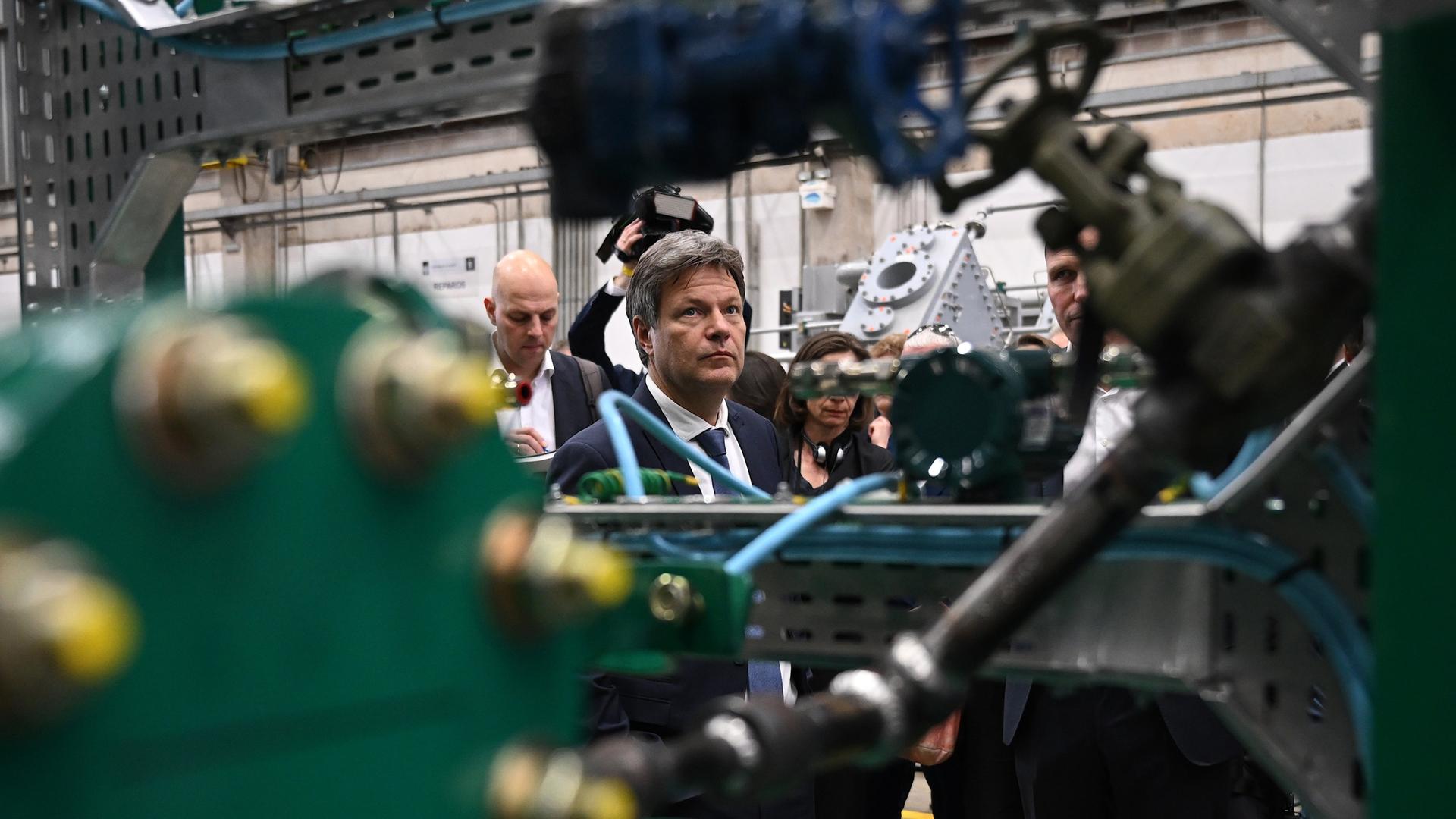 Robert Habeck steht während einer Führung durch die Firma Neuman & Esser in einer Halle und betrachtet eine große grüne Maschine. Robert Habeck steht während einer Führung durch die Firma Neuman & Esser in einer Halle und betrachtet eine große grüne Maschine.