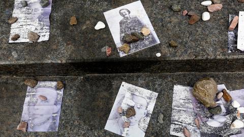 Kleine Steine liegen einer jüdischen Tradition entsprechend auf alten Fotos, die Opfer des Massakers in Babyn Jar 1941 zeigen.