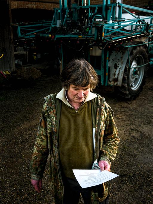 Eckhardt Heukamp vor einem Traktor mit einem Brief in der Hand