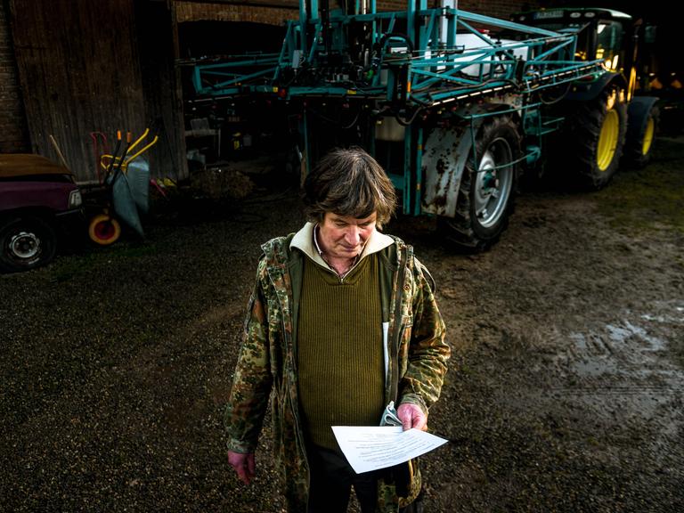 Eckhardt Heukamp vor einem Traktor mit einem Brief in der Hand