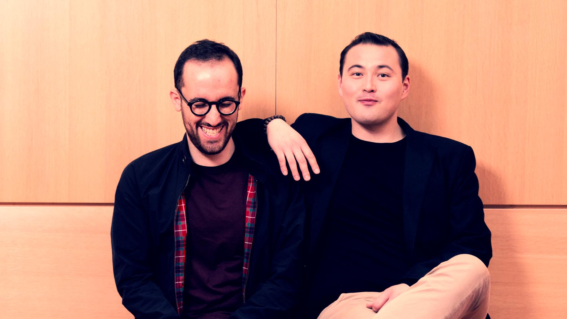 Die beiden Interpreten sitzen beieinander auf einer holzumtäfelten, modernen Bank, wobei der Sänger Simon Bode seinen rechten Ellenbogen auf die Schulter des Pianisten Igor Levit lehnt. Die beiden Interpreten sitzen beieinander auf einer holzumtäfelten, modernen Bank, wobei der Sänger Simon Bode seinen rechten Ellenbogen auf die Schulter des Pianisten Igor Levit lehnt.