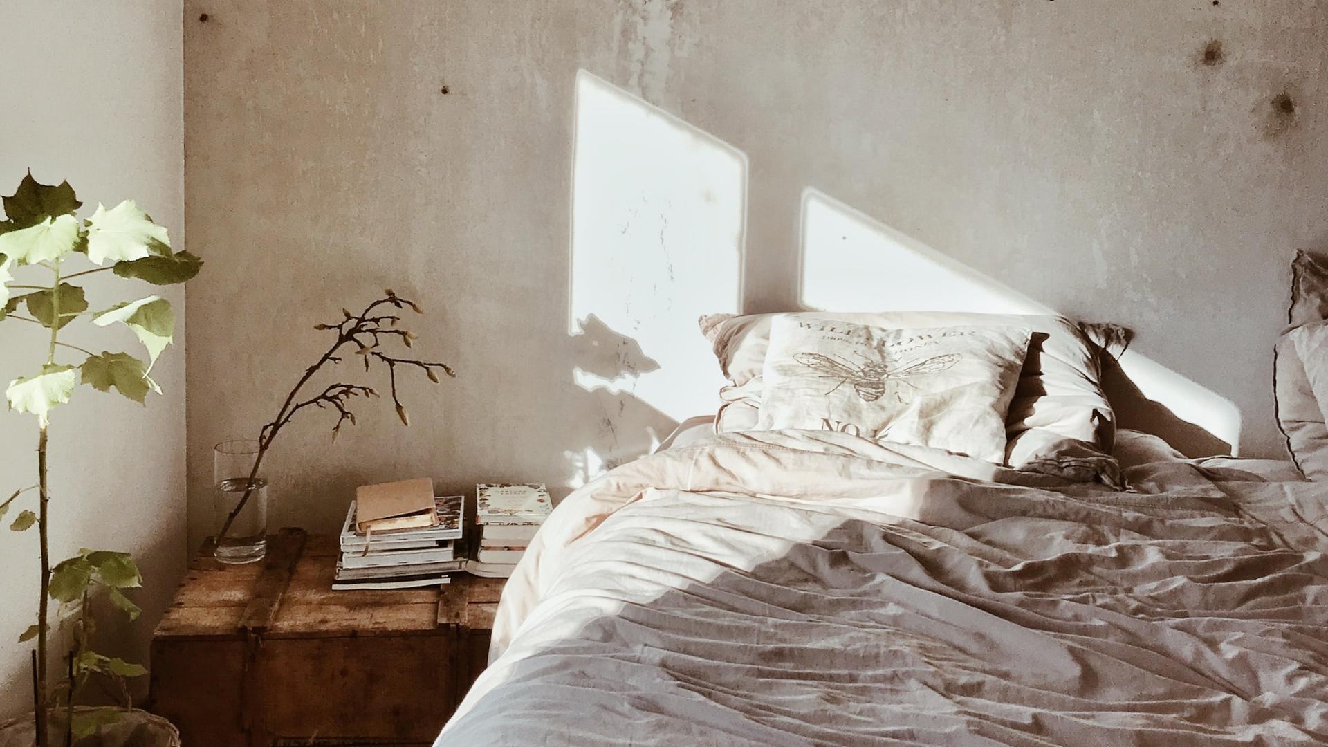 Auf ein leeres Bett vor unverputzter Wand strahlt die Sonne