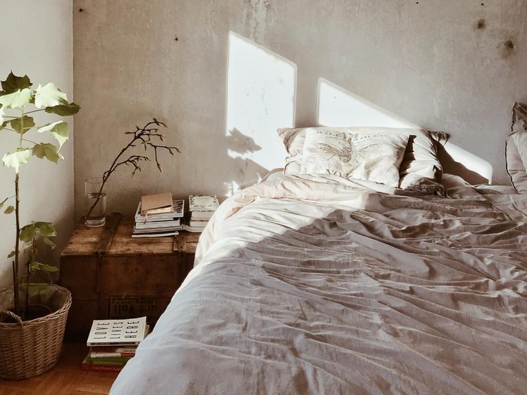Auf ein leeres Bett vor unverputzter Wand strahlt die Sonne