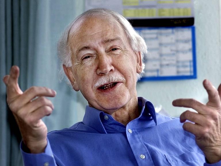Hermann Bausinger lächelnd und fröhlich gestikulierend.