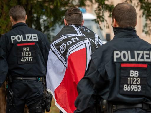"Reichsbürger"-Demonstration im November 2020 in Potsdam: Ein Demonstrant mit einer schwarzrotweißen Flagge mit einem Eisernen Kreuz darauf wird von zwei Polizisten abgeführt.