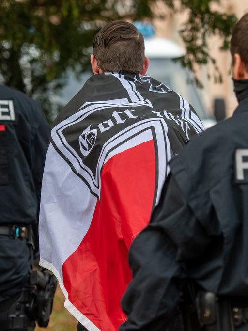 "Reichsbürger"-Demonstration im November 2020 in Potsdam: Ein Demonstrant mit einer schwarzrotweißen Flagge mit einem Eisernen Kreuz darauf wird von zwei Polizisten abgeführt.