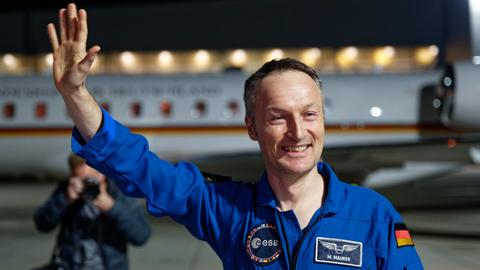 Der Astronaut Matthias Maurer steht nach seiner Ankunft auf dem Flughafen Köln/Bonn auf dem Vorfeld vor iner Maschine der Luftwaffe und winkt.