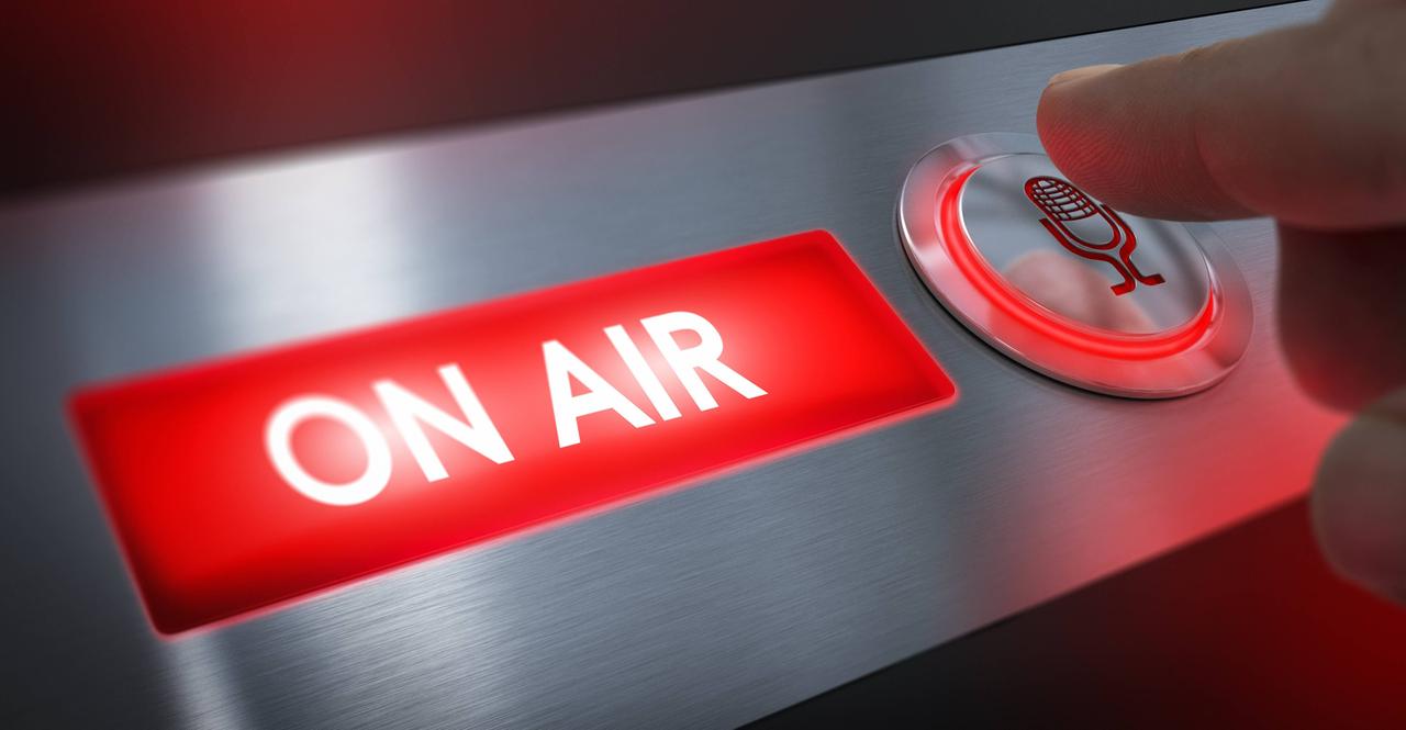 Rotes Schild mit der Aufschrift "On air". Daneben ist ein Finger zu sehen, der auf eine Taste mit Mikrofonsymbol drückt. Rotes Schild mit der Aufschrift "On air". Daneben ist ein Finger zu sehen, der auf eine Taste mit Mikrofonsymbol drückt.