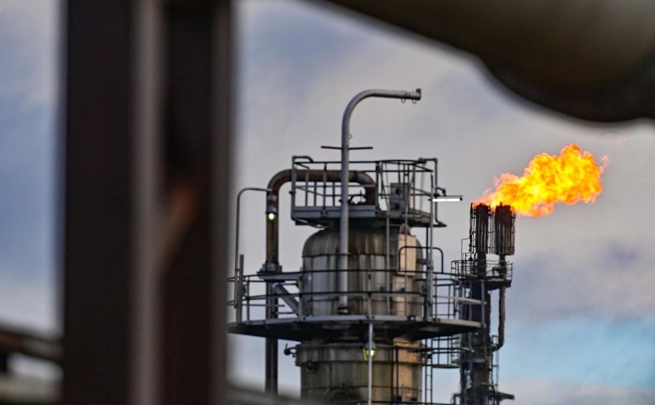 Aus dem Turm einer Erdölraffinerie stößt eine Flamme hervor. Aus dem Turm einer Erdölraffinerie stößt eine Flamme hervor.