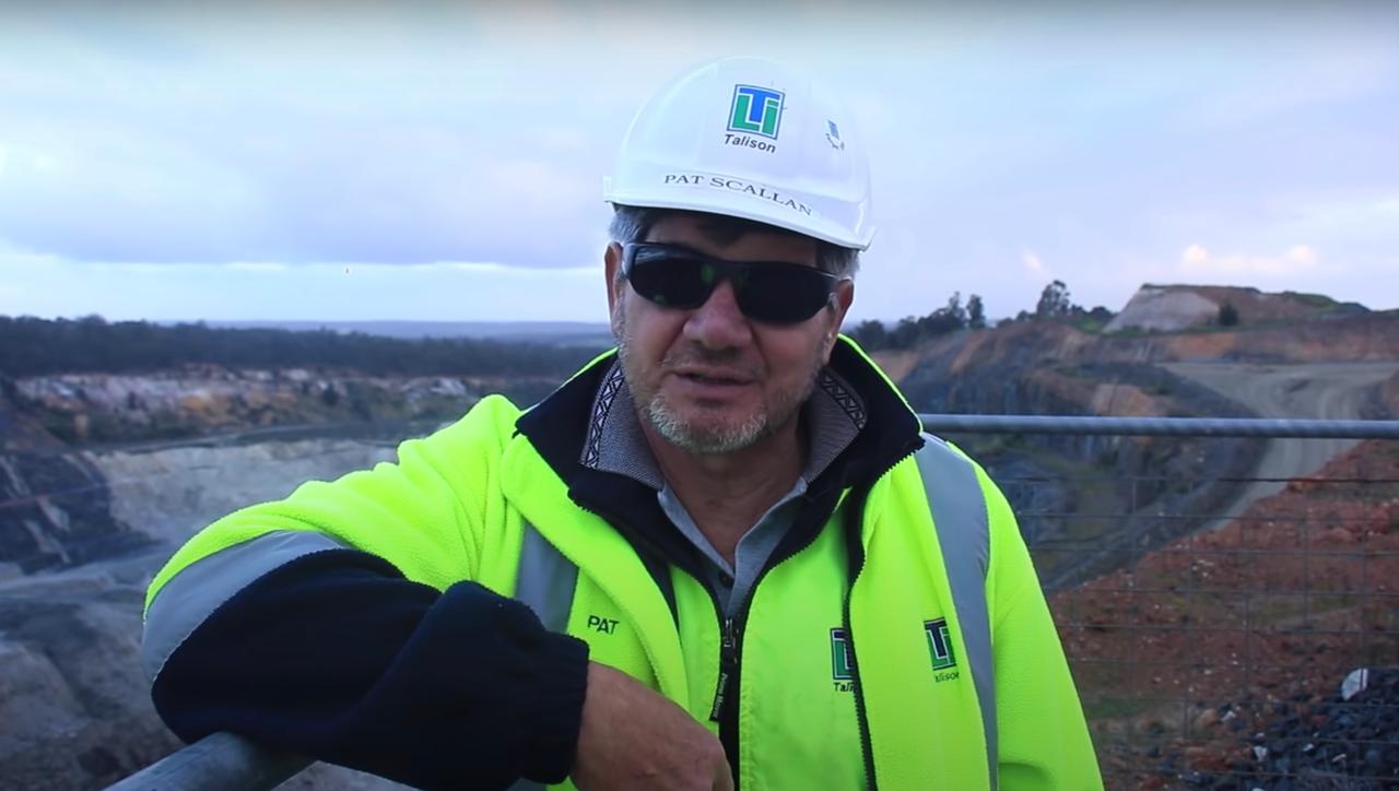 Ein Mann mit Helm, Sonnenbrille und Warnweste steht am Rand einer Grube. Ein Mann mit Helm, Sonnenbrille und Warnweste steht am Rand einer Grube.