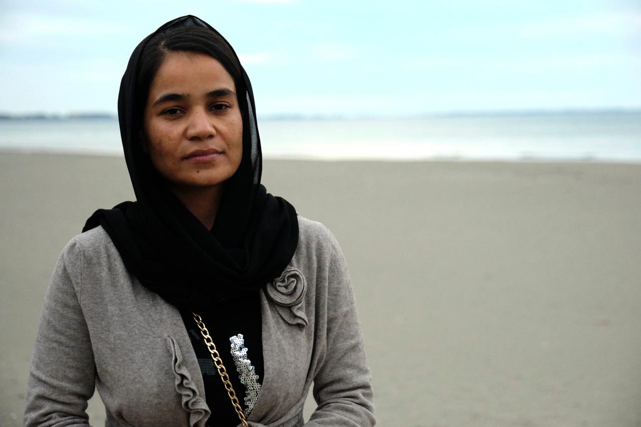 Ziagul Azimi steht am Strand vor dem Wasser. Sie trägt ein schwarzes Kopftuch und eine graue Jacke. Ziagul Azimi steht am Strand vor dem Wasser. Sie trägt ein schwarzes Kopftuch und eine graue Jacke.