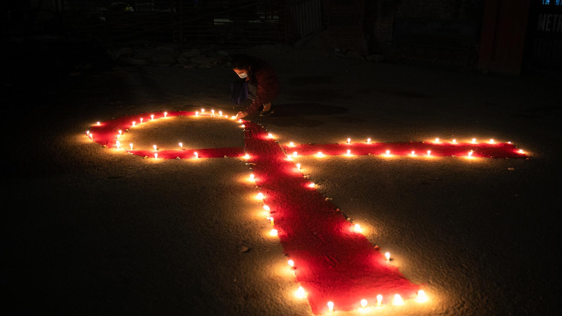 Viele Kerzen formen eine rote Schleife anlässlich des Welt-Aids-Tages Viele Kerzen formen eine rote Schleife anlässlich des Welt-Aids-Tages