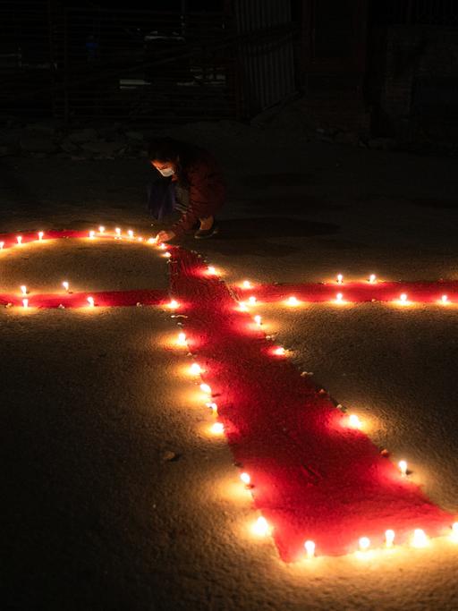 Viele Kerzen formen eine rote Schleife anlässlich des Welt-Aids-Tages