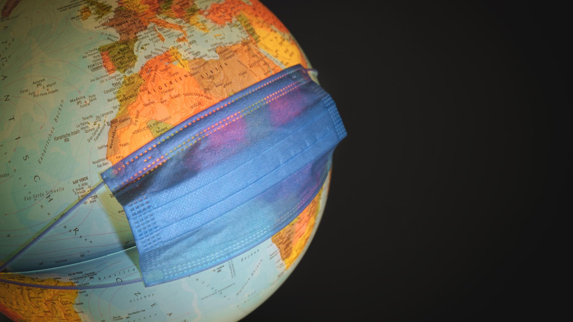 Ein Globus mit einer OP-Maske über dem afrikanischen Kontinent Ein Globus mit einer OP-Maske über dem afrikanischen Kontinent