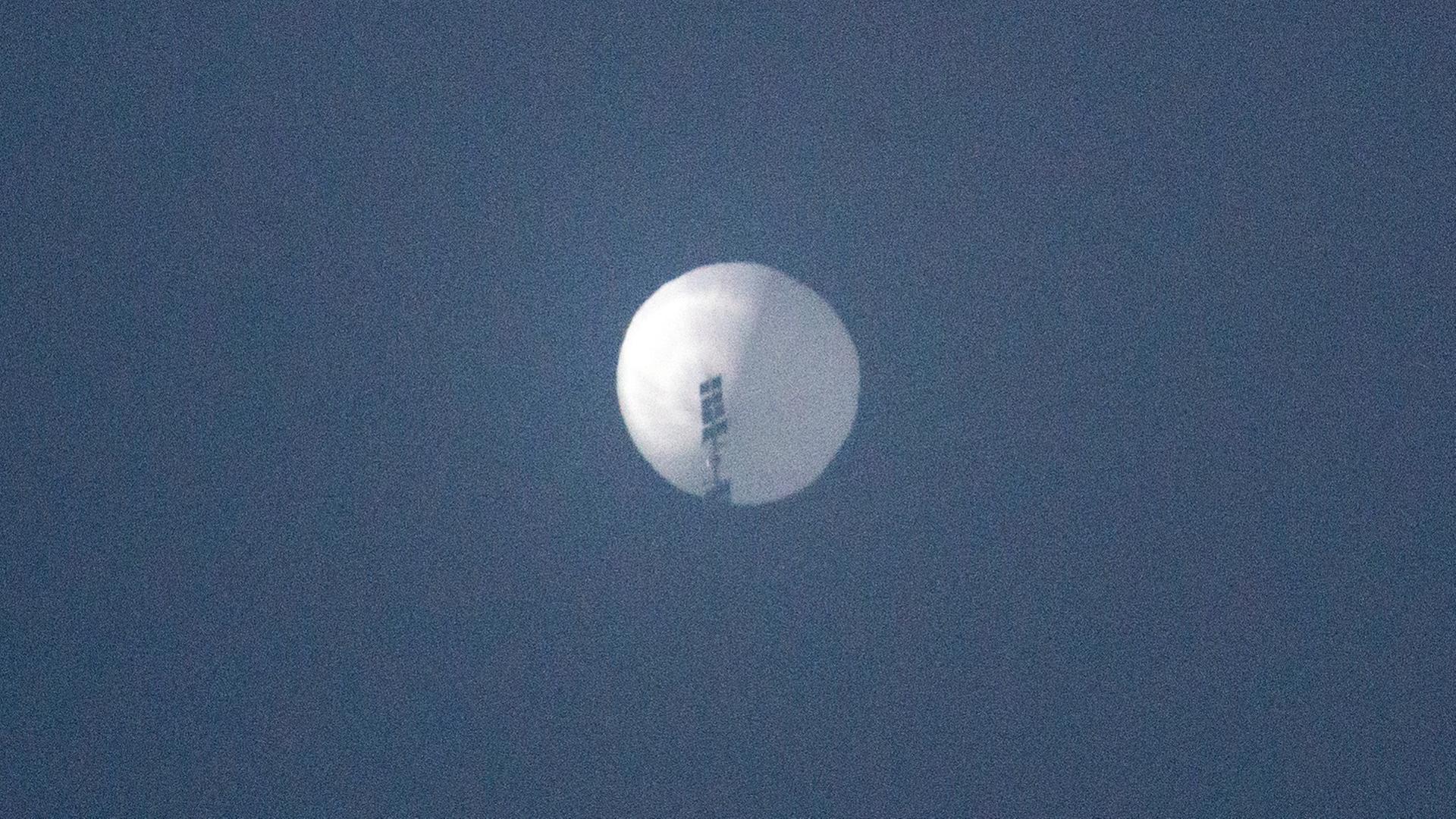 Ein großer weißer Ballon schwebt am blauen Himmel.