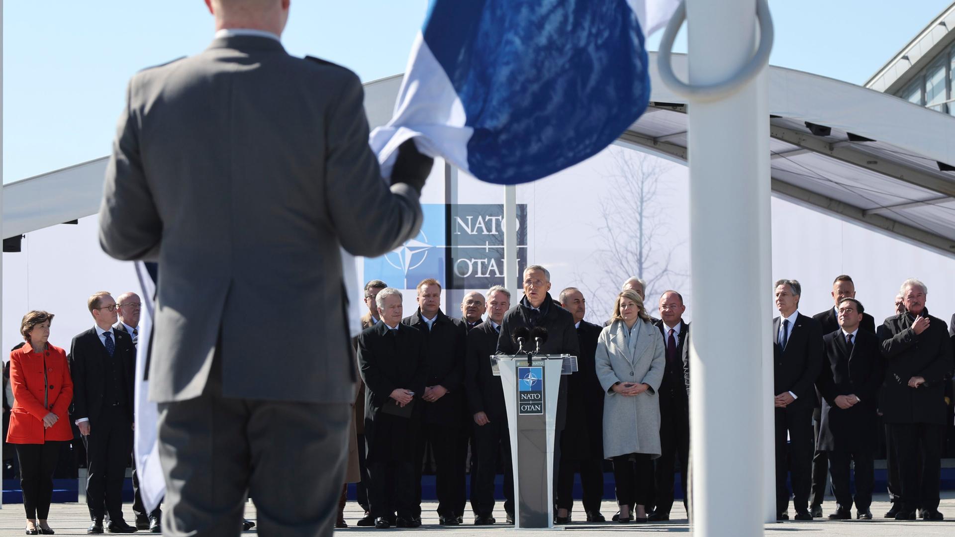 Die Fahne von dem Land Finnland wird vor dem Haupt-Quartier von der NATO hoch-gezogen. Die Fahne von dem Land Finnland wird vor dem Haupt-Quartier von der NATO hoch-gezogen.