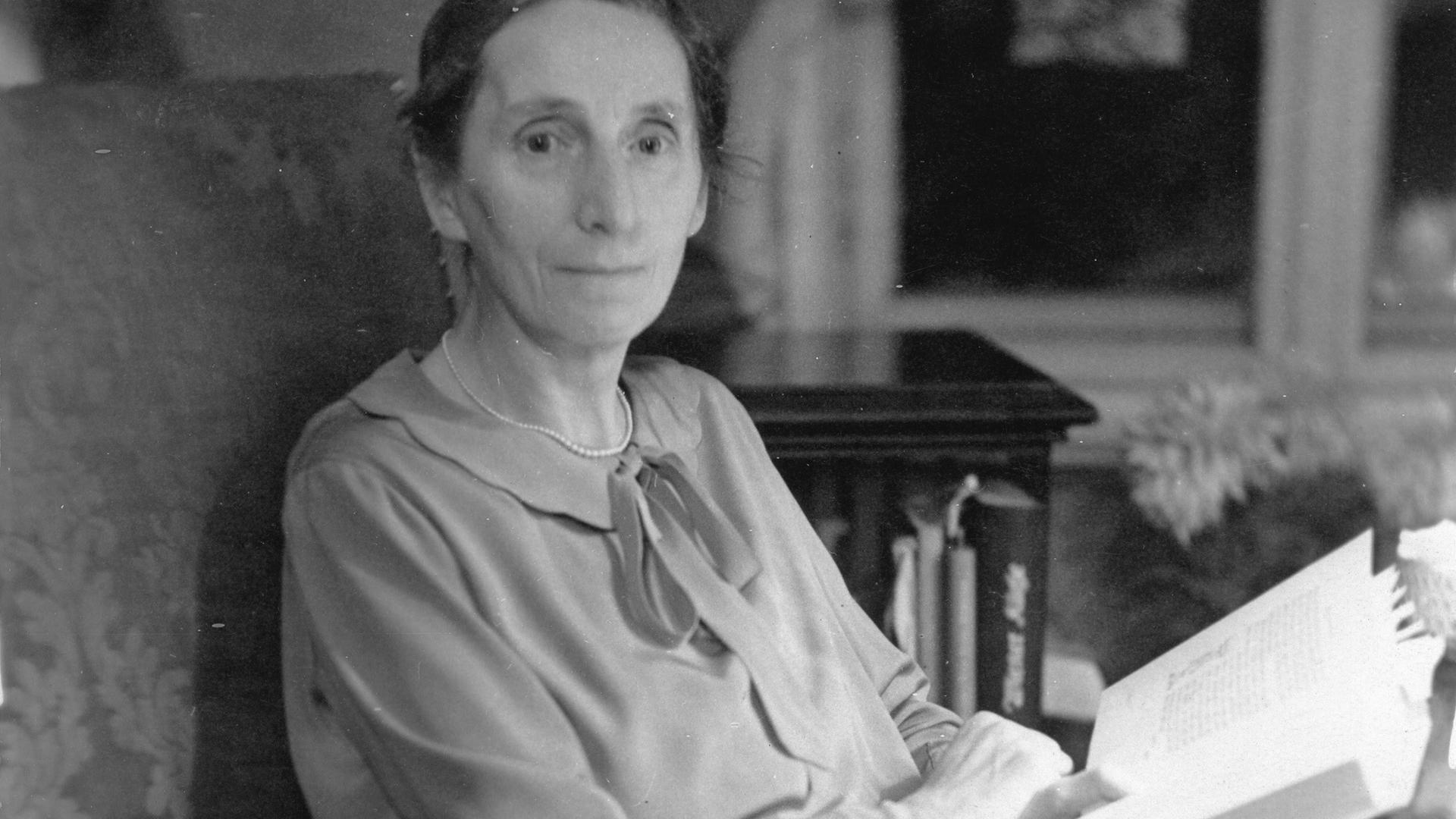 Alice Salomon, Gründerin der ersten Sozialen Frauenschule in Berlin, sitzt auf einer Fotografie von 1929 in einem Sessel und liest ein Buch.