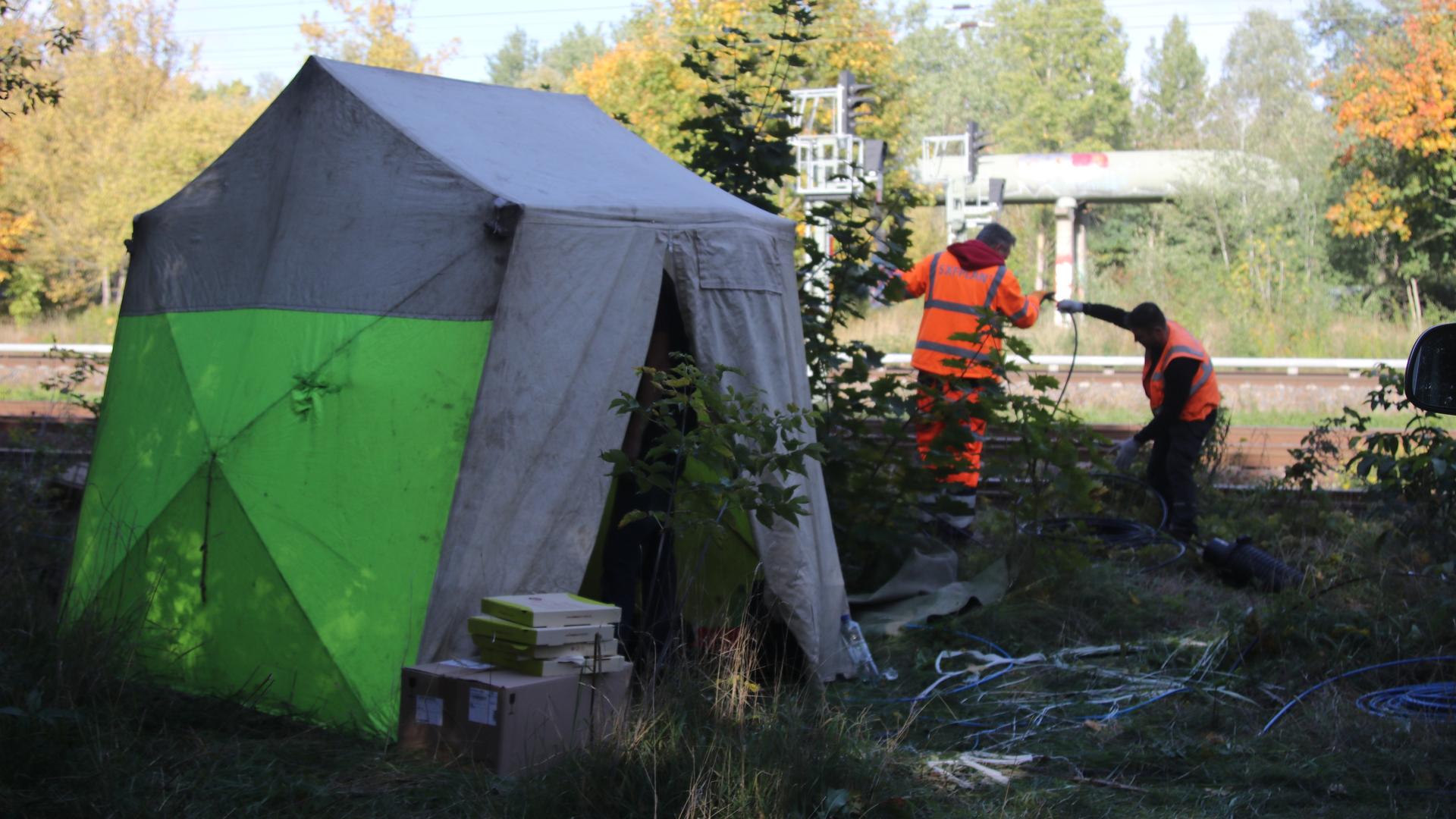 Zwei Arbeiter mit orangefarbenen Warnwesten reparieren das Kabel in der Nähe von Berlin. Zwei Arbeiter mit orangefarbenen Warnwesten reparieren das Kabel in der Nähe von Berlin.